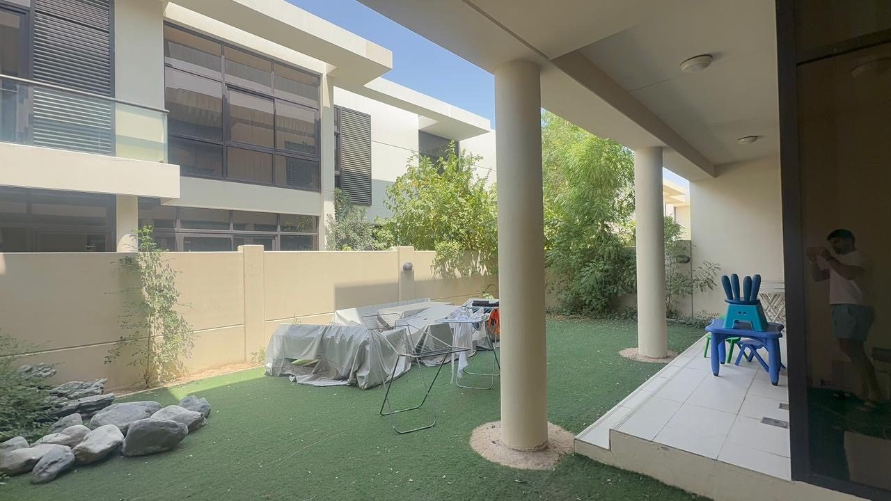 Villa garden as filmed on a phone: dust sheets, a drying rack, a child's table, and a person in the doorway